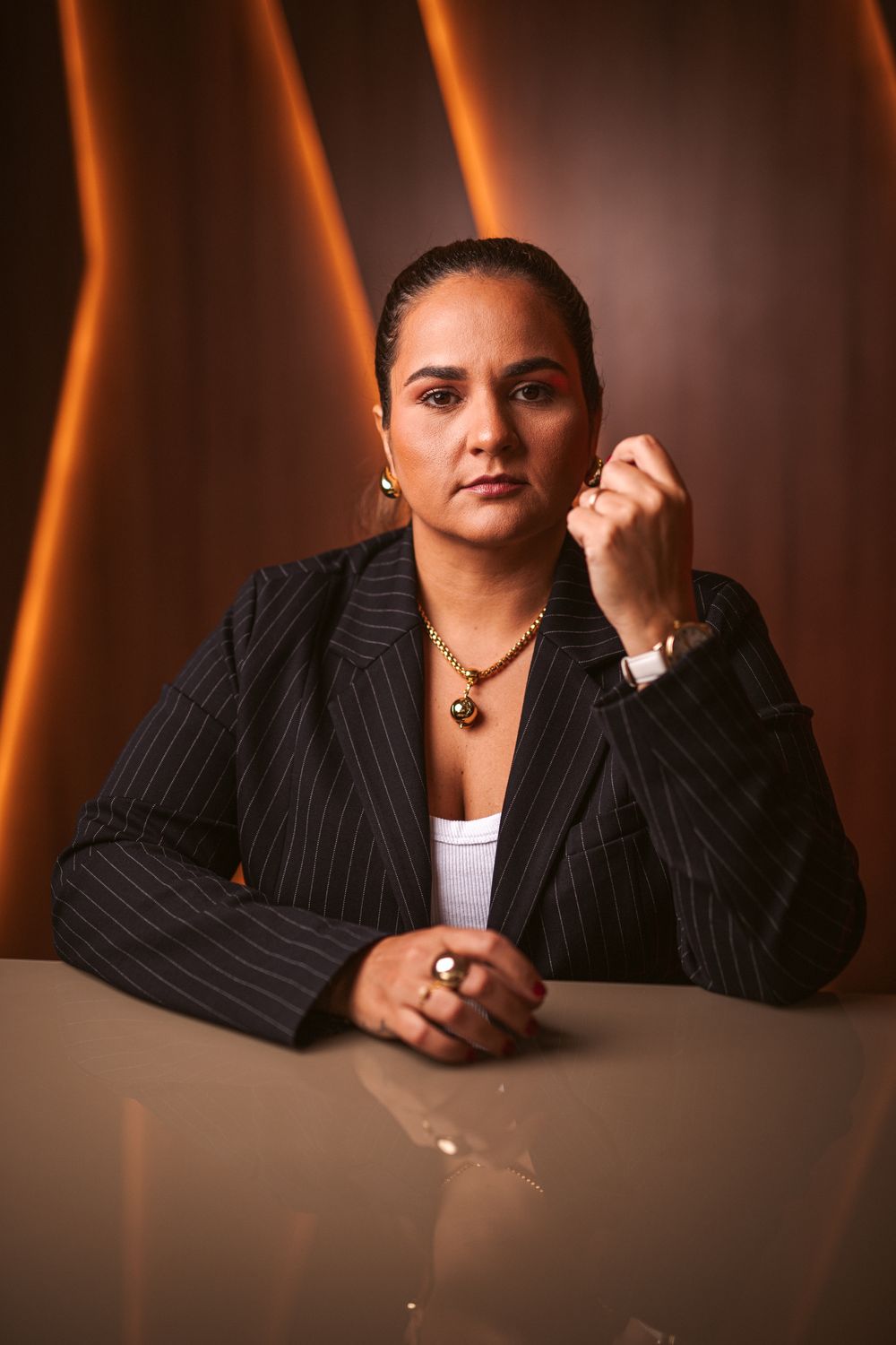 Roxane Plácido, estrategista de marketing médico, sentada à mesa com luz laranja ao fundo
